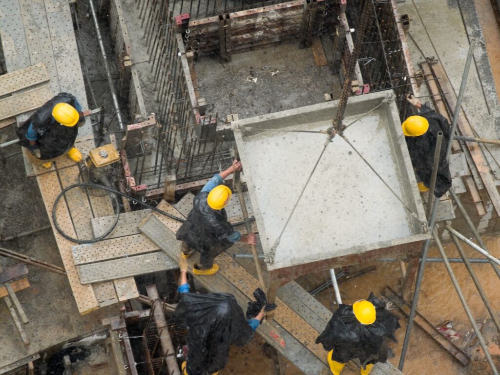 Construction workers adjusting a funnel of concrete for pouring